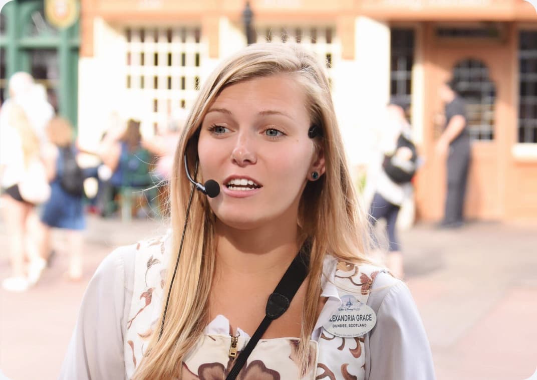 Alexandria at a theme park, speaking into a headset microphone